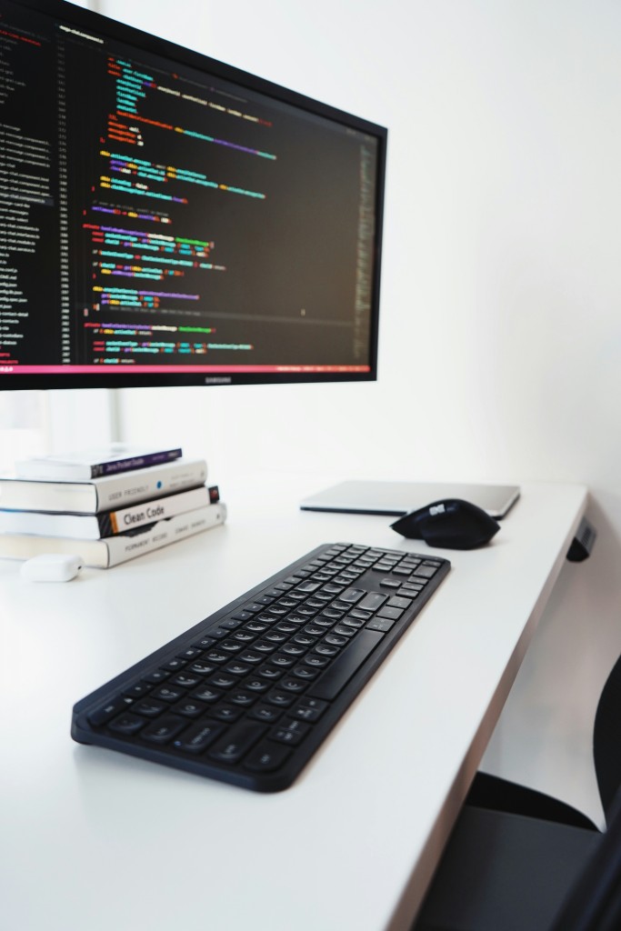 black computer keyboard on white desk with code on screen by Morgan Richardson on Unsplash
